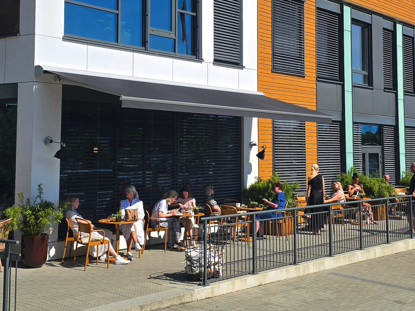 Screens montert på restaurantfasade for solskjerming av uteservering